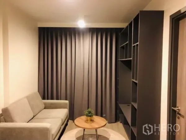 คอนโด ให้เช่าหรือขายในPathum Wan, Bangkok - ห้องนั่งเล่นอบอุ่น ผ้าม่านสีเทา โซฟา ชั้นบิลท์อิน และโต๊ะกาแฟทรงกลม