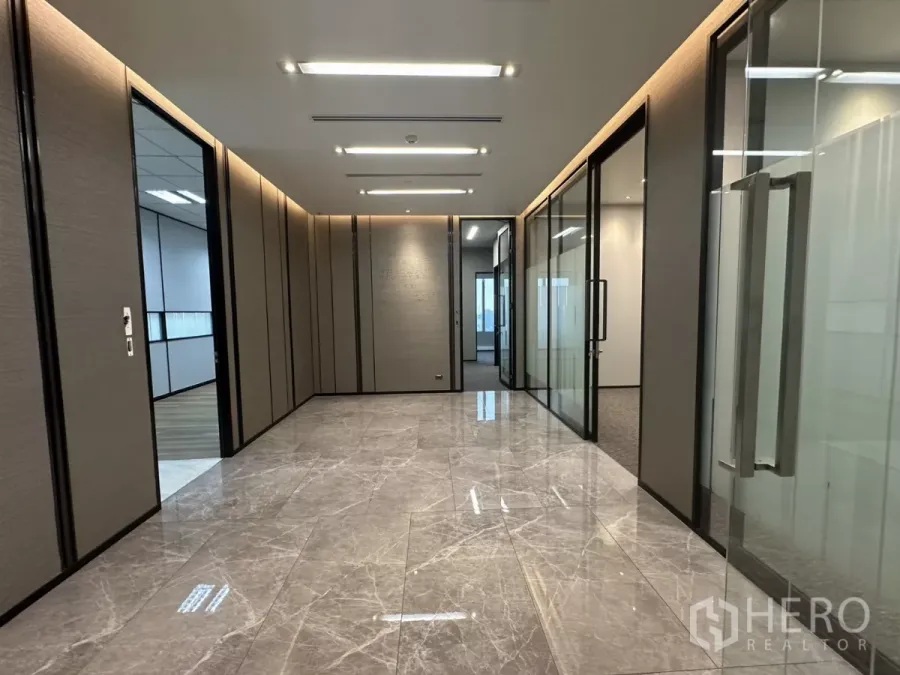 办公空间 出租在Watthana, Bangkok - 大理石地面的走廊，玻璃隔间与嵌入式灯光的高端办公区。