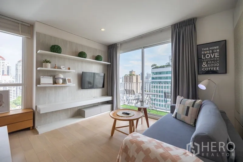 Condominium for rent in Watthana, Bangkok - Dining zone adjacent to a minimalist kitchen and display shelves by a bright window.