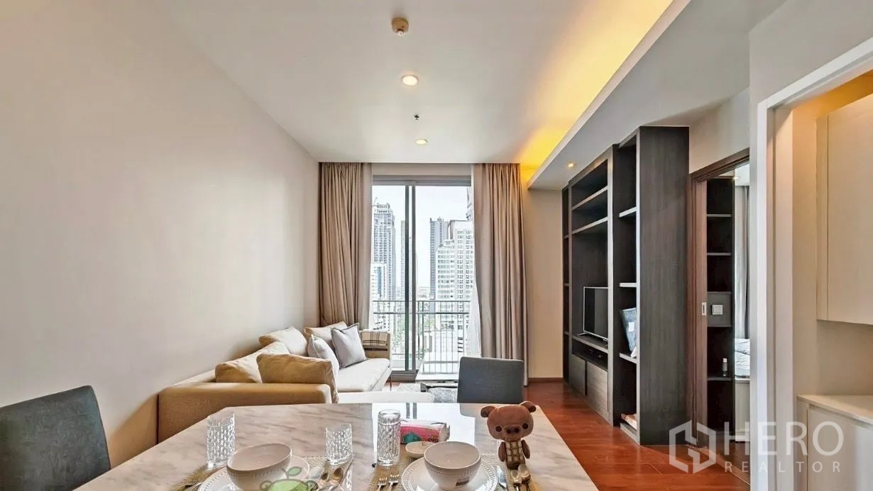 คอนโด ให้เช่าในWatthana, Bangkok - ห้องนั่งเล่นและรับประทานอาหารแบบเปิด พร้อมโซฟาเข้ามุม ชั้นวางทีวีบิวท์อิน พื้นไม้ และประตูกระจกบานเลื่อนออกสู่ระเบียงวิวสกายไลน์กรุงเทพฯ