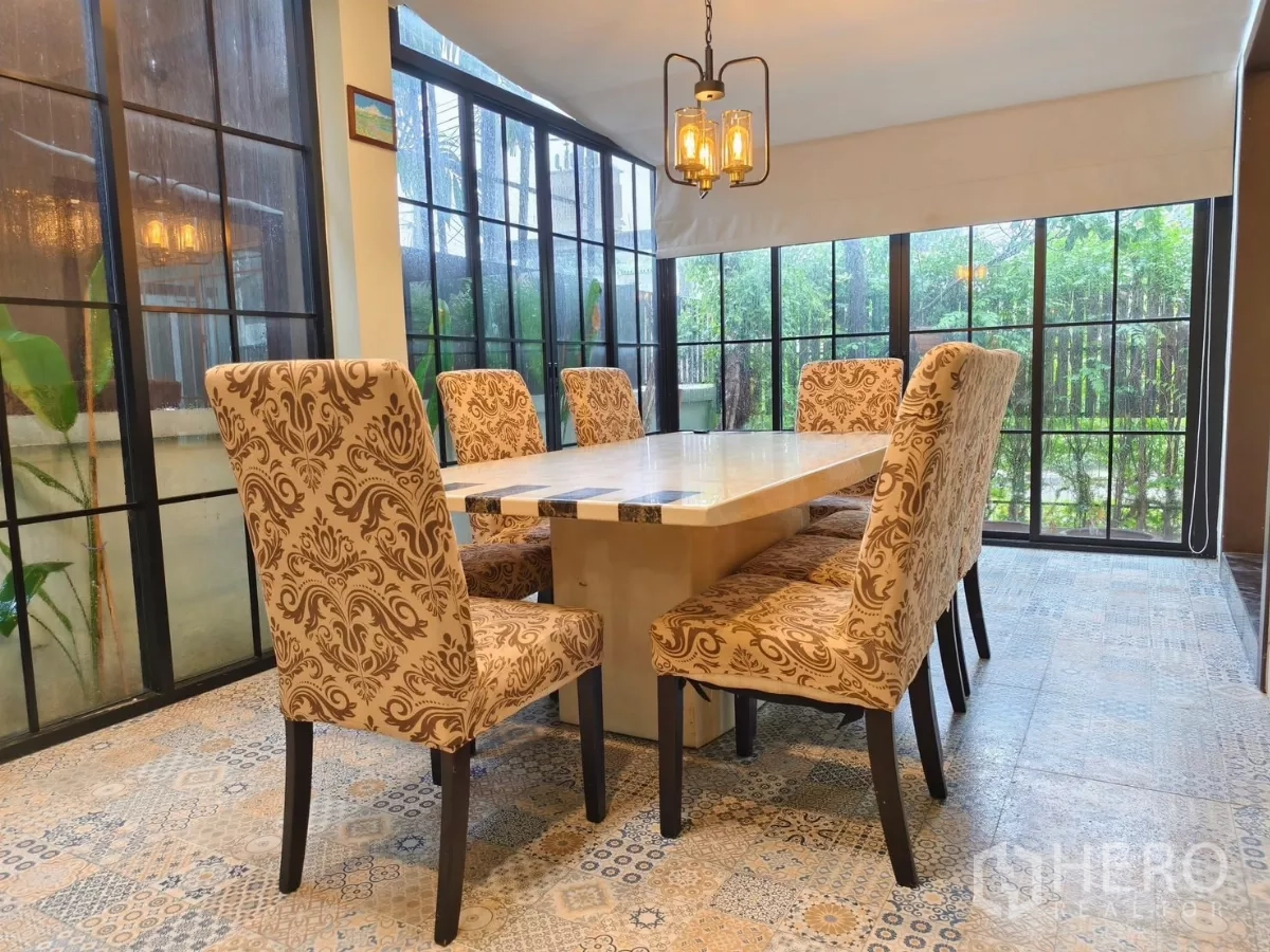 Detached House for rent in Bang Kapi, Bangkok - Bright dining room for eight with patterned chairs and full-height windows.