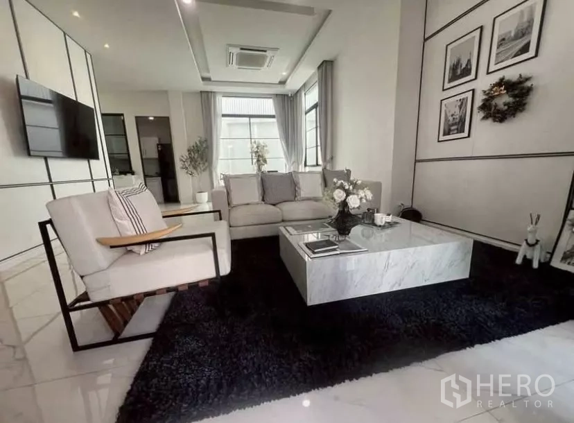 独立式住宅 出租在Lat Phrao, Bangkok - 采光充足的客厅，沙发组合、石材茶几与壁挂电视。