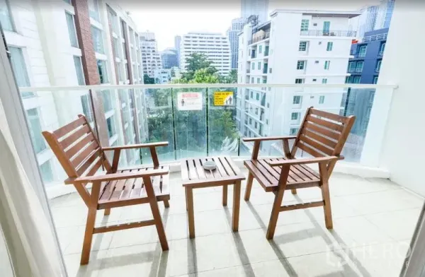 公寓 出租在Khlong Toei, Bangkok - 阳台配两把木椅与小桌，可眺望城市与绿意