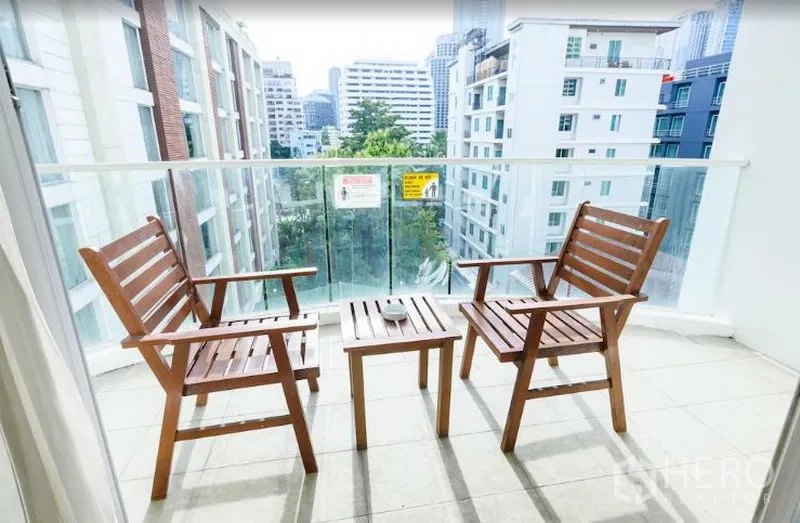 公寓 出租在Khlong Toei, Bangkok - 阳台配两把木椅与小桌，可眺望城市与绿意