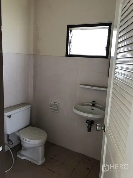 Shophouse for sale in Lam Luk Ka, Pathum Thani - Compact bathroom with toilet, sink, and a small louvered window.