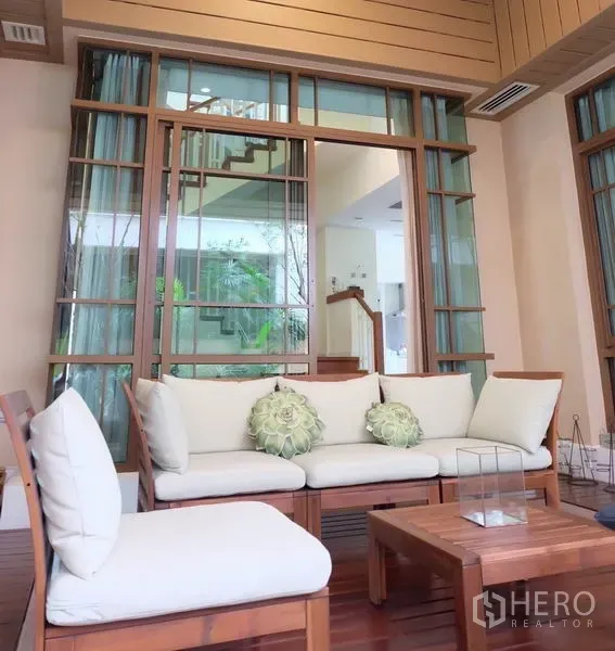 Detached House for rent in Watthana, Bangkok - Covered terrace with cushioned wooden seating and glass doors opening to the home.
