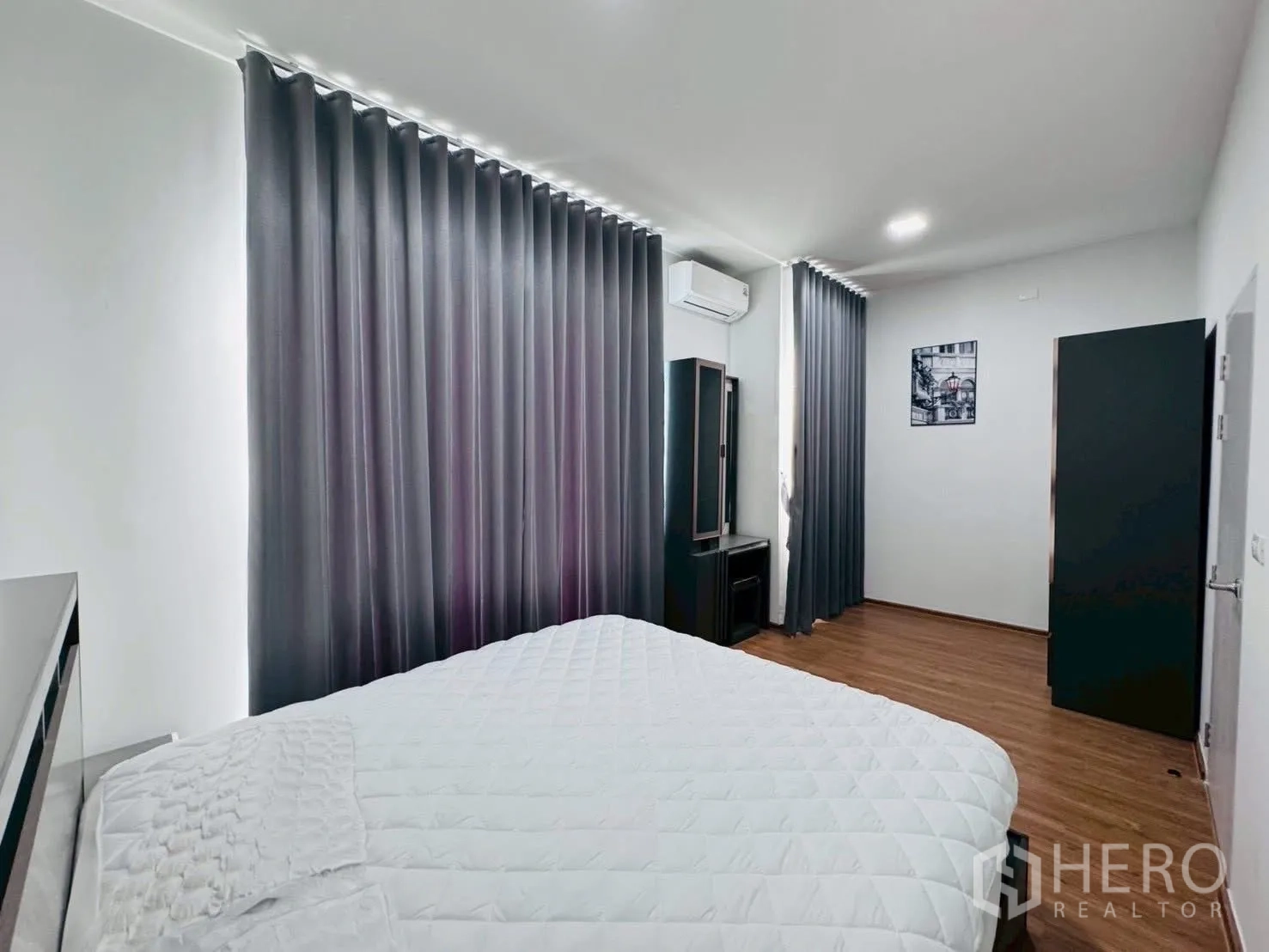 ทาวน์เฮาส์ for rent in Bang Phli, Samut Prakan - ห้องนอนมาสเตอร์กว้าง เตียงใหญ่ ผ้าม่านสีเทา พื้นไม้ พร้อมโต๊ะเครื่องแป้ง