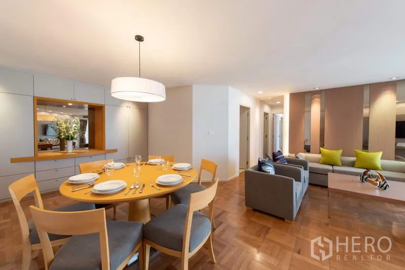 Apartment for rent - Open-plan dining and living area with round table, pendant light, built-in cabinetry and parquet floors in a Bangkok apartment near MRT Lumphini.