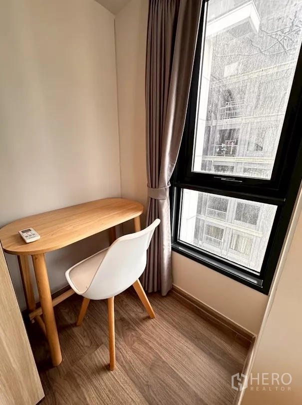 Condominium for rent in Chatuchak, Bangkok - Compact study nook with wooden desk and chair by the window.