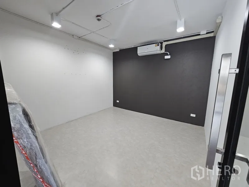 零售空间 出租 - 封闭式房间，深色特色墙、分体空调与明亮射灯。