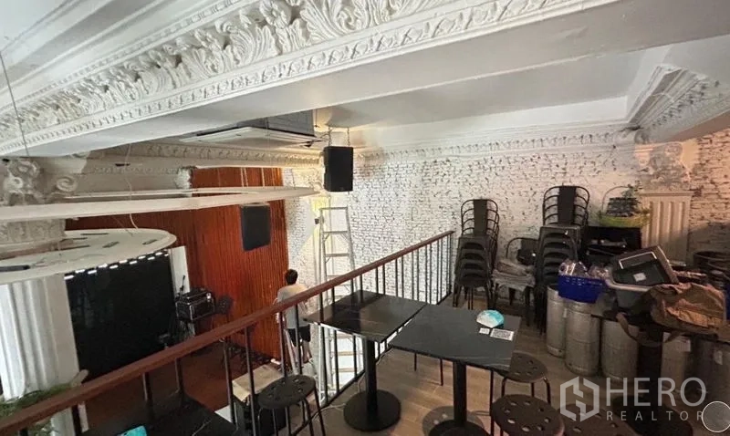 Shophouse for sale - Mezzanine seating area with ornate white cornices and exposed brick wall.