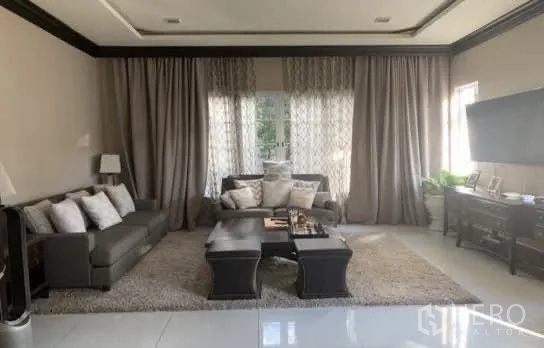 Detached House for sale in Bang Phli, Samut Prakan - Comfortable living room with sofas, TV console, full-height curtains, and glossy tiled flooring.