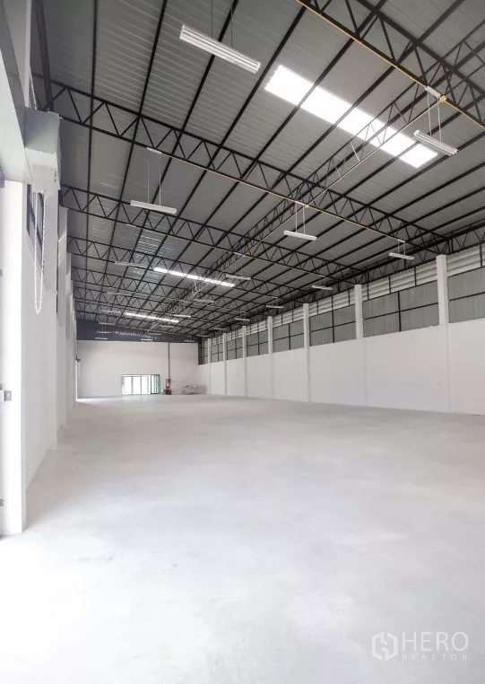 Factory for rent or sale in Bang Len, Nakhon Pathom - Warehouse interior facing the loading exit and glass office entrance at the far end.