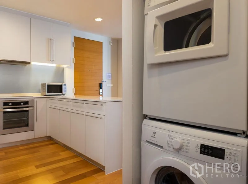 คอนโด ให้เช่าในBang Kho Laem, Bangkok - ทางเข้าครัวพร้อมเครื่องซักผ้าและอบผ้าแบบตั้งซ้อน ข้างตู้เก็บของและประตูไม้