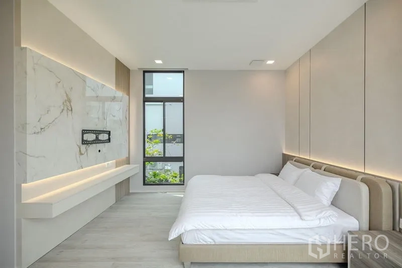 Detached House for rent in Saphan Sung, Bangkok - Bedroom with marble accent TV wall and tall window.
