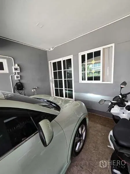 Detached House for rent in Thanyaburi, Pathum Thani - Enclosed garage bay with sliding glass door, grey wall and parking for a car and scooter.
