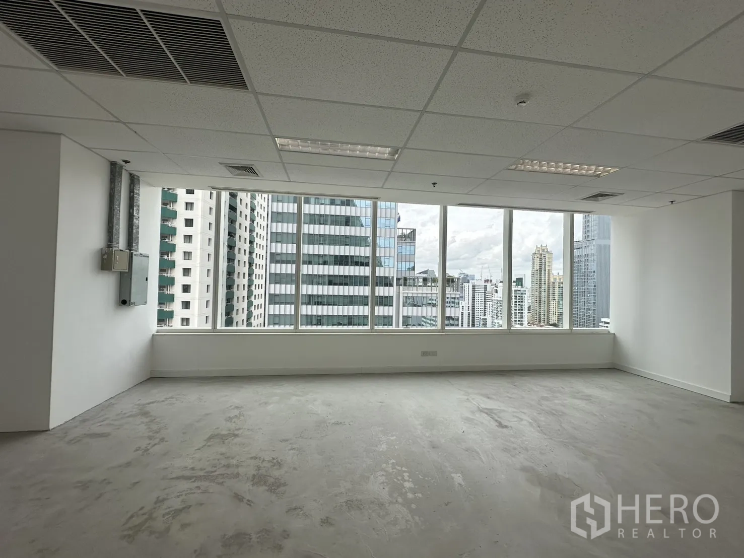 ออฟฟิศ for rent in Watthana, Bangkok - พื้นที่สำนักงานเปล่า ฝ้าเพดานทีบาร์พร้อมไฟ และวิวสกายไลน์ผ่านหน้าต่างยาว.