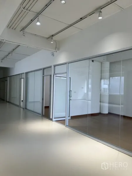 Office Space for rent in Bang Rak, Bangkok - Bright corridor with ceiling spotlights and glass-partitioned meeting rooms.