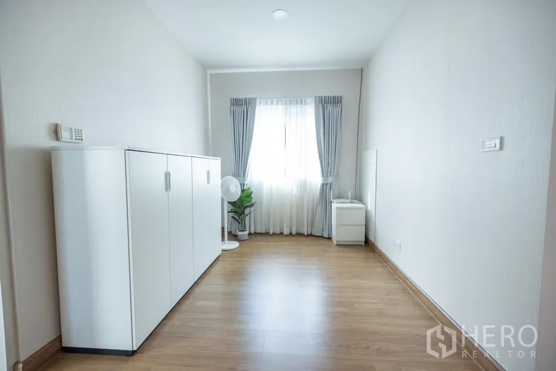 Detached House for sale in Prawet, Bangkok - Minimalist multipurpose room with white cabinet, window and warm wood flooring.