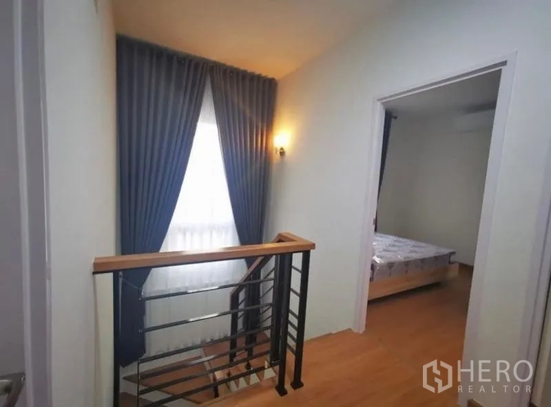 独立式住宅 出租 - 楼梯平台，金属栏杆与深色窗帘的窗户。