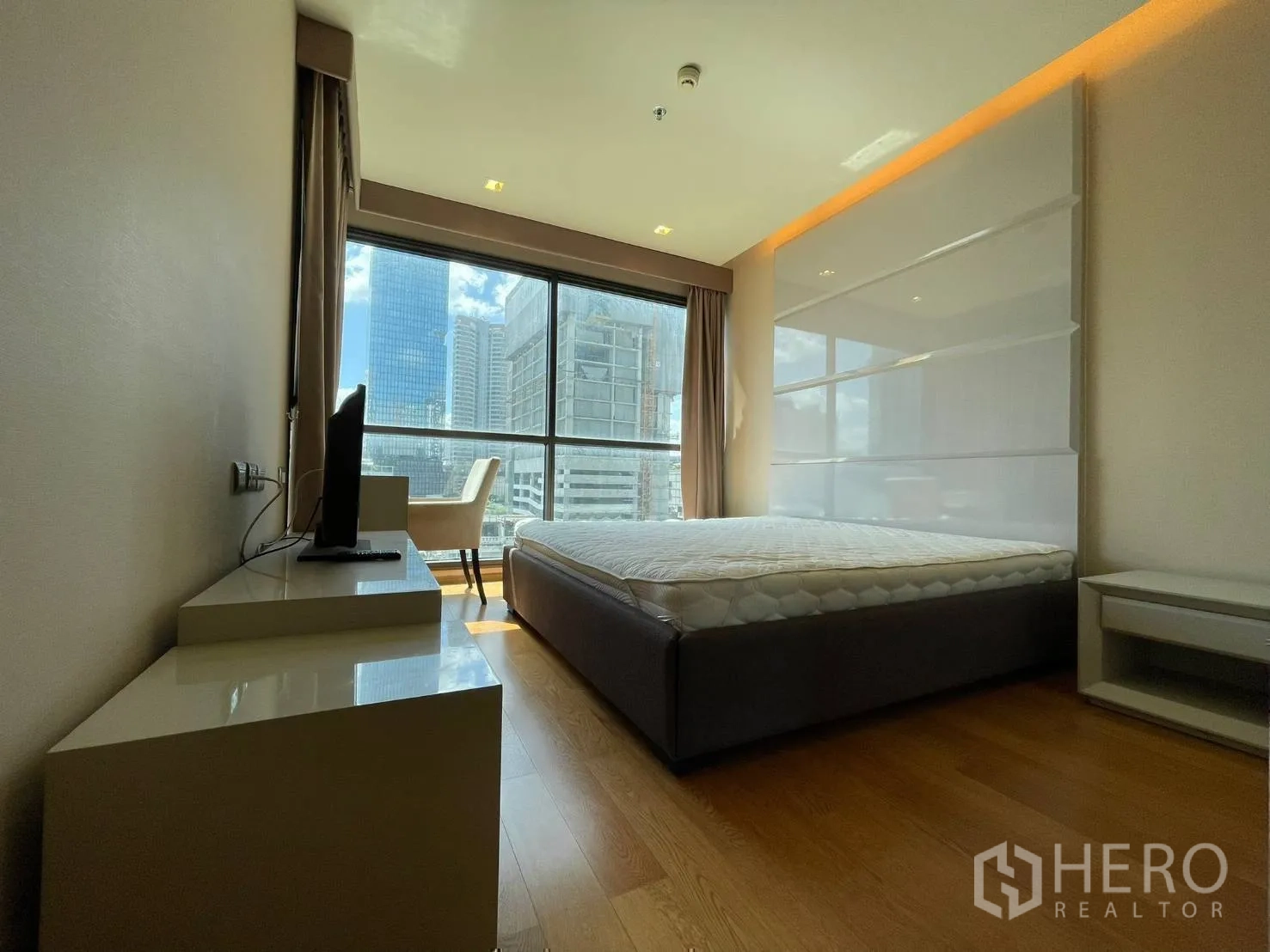 Condominium for rent or sale in Bang Rak, Bangkok - Bright bedroom with large bed, desk and floor-to-ceiling window with city view.