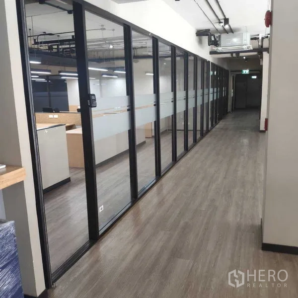 办公空间 出租 - 走廊一侧为落地玻璃隔间，木纹地面紧邻办公区。