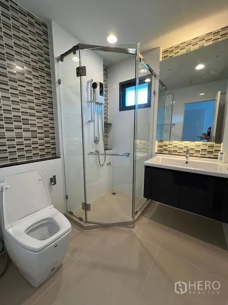 Detached House for rent in Bang Kapi, Bangkok - Bathroom with corner glass shower, toilet and mosaic accent tiles.