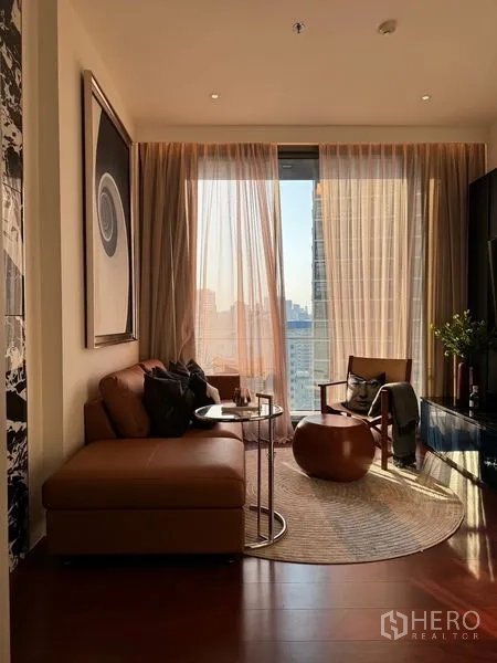 Condominium for sale in Watthana, Bangkok - Living room panorama with sofa, armchair and Bangkok skyline beyond a floor-to-ceiling window.