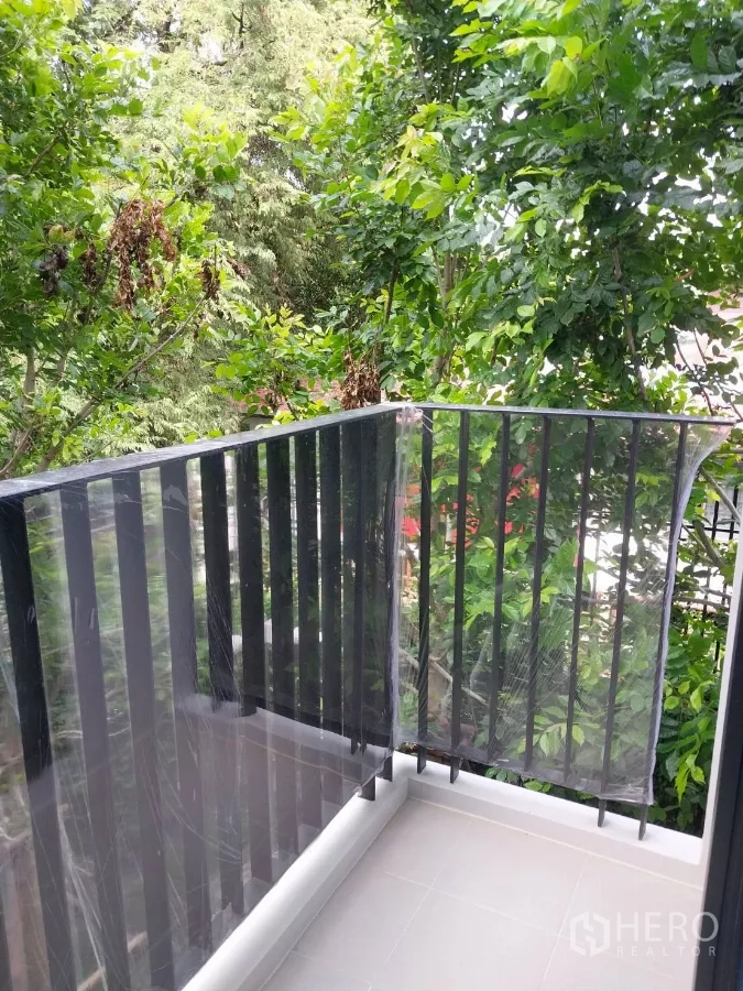 Townhouse for rent in Khlong Toei, Bangkok - Corner balcony with black metal railings and leafy surroundings.