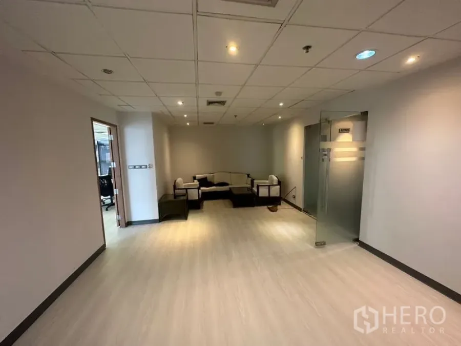 办公空间 出租 - 接待休息区，沙发组合、筒灯照明与磨砂玻璃门。