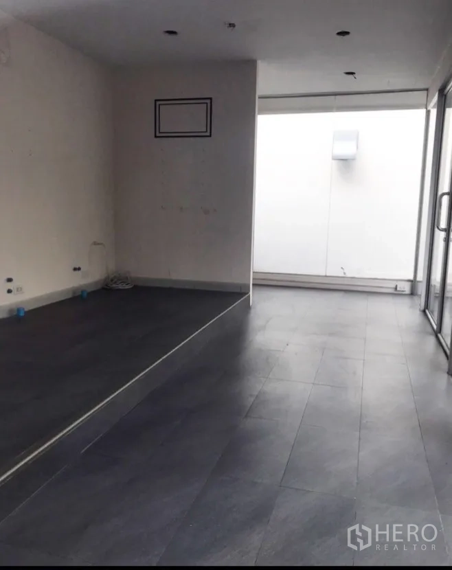 零售空间 出租在Watthana, Bangkok - 空置店内，灰色地砖、白色天花与推拉玻璃门。