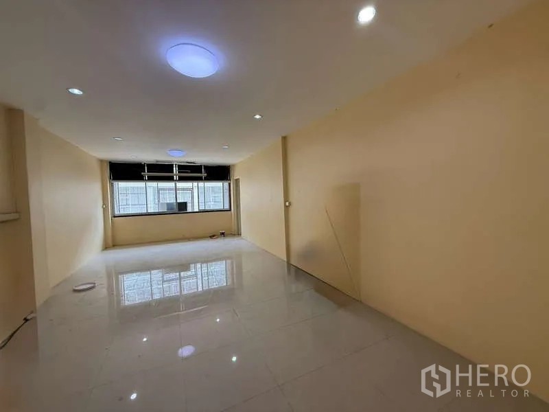 Home Office for rent in Khlong Toei, Bangkok - Large empty room with glossy white tiles and a wide window bringing in natural light.