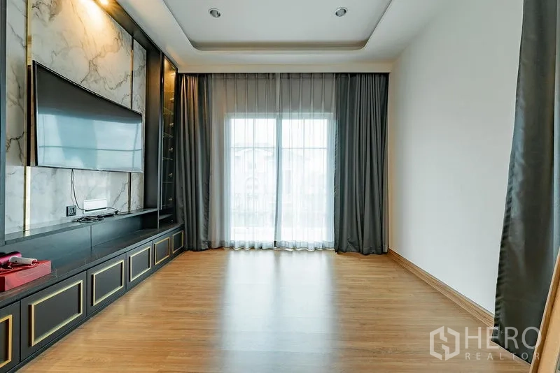 บ้าน ให้เช่าหรือขายในBang Khen, Bangkok - ห้องกว้างปูพื้นไม้ บิลท์อินชั้นวางทีวีโทนเข้ม และประตูบานเลื่อนออกระเบียง