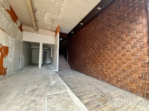 Shophouse for rent in Sathon, Bangkok - Deep shop space with textured feature wall and stairs leading to the upper floor.