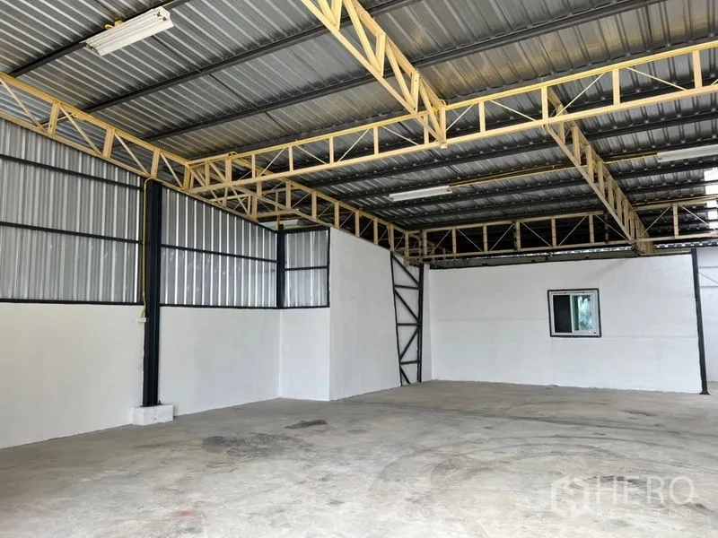 Warehouse for rent in Suan Luang, Bangkok - Spacious warehouse interior featuring a steel truss roof, fluorescent lighting, and a concrete floor.