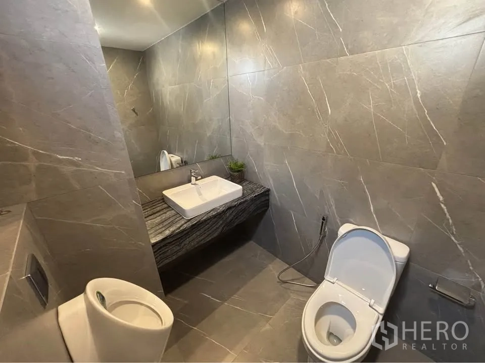 Home Office for rent or sale in Suan Luang, Bangkok - Spacious powder room with long stone counter, wide mirror, and toilet.