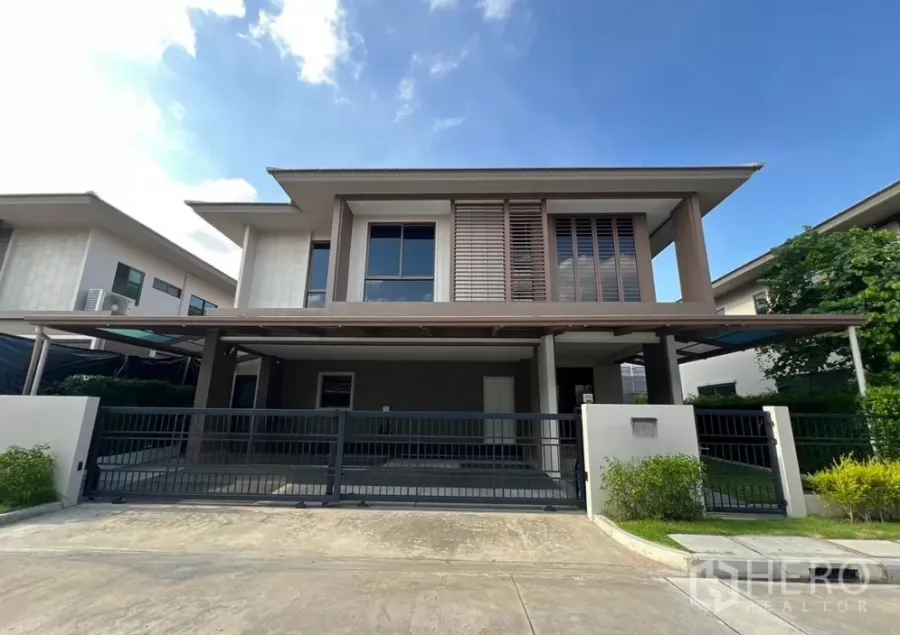 Detached House for rent or sale in Bang Kapi, Bangkok - Front exterior of a modern two-storey detached house with a gated driveway and covered carport