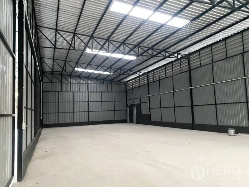 Warehouse for rent in Wang Thonglang, Bangkok - Bright clear-span warehouse interior with roof light panels, large sliding door, and durable floor.