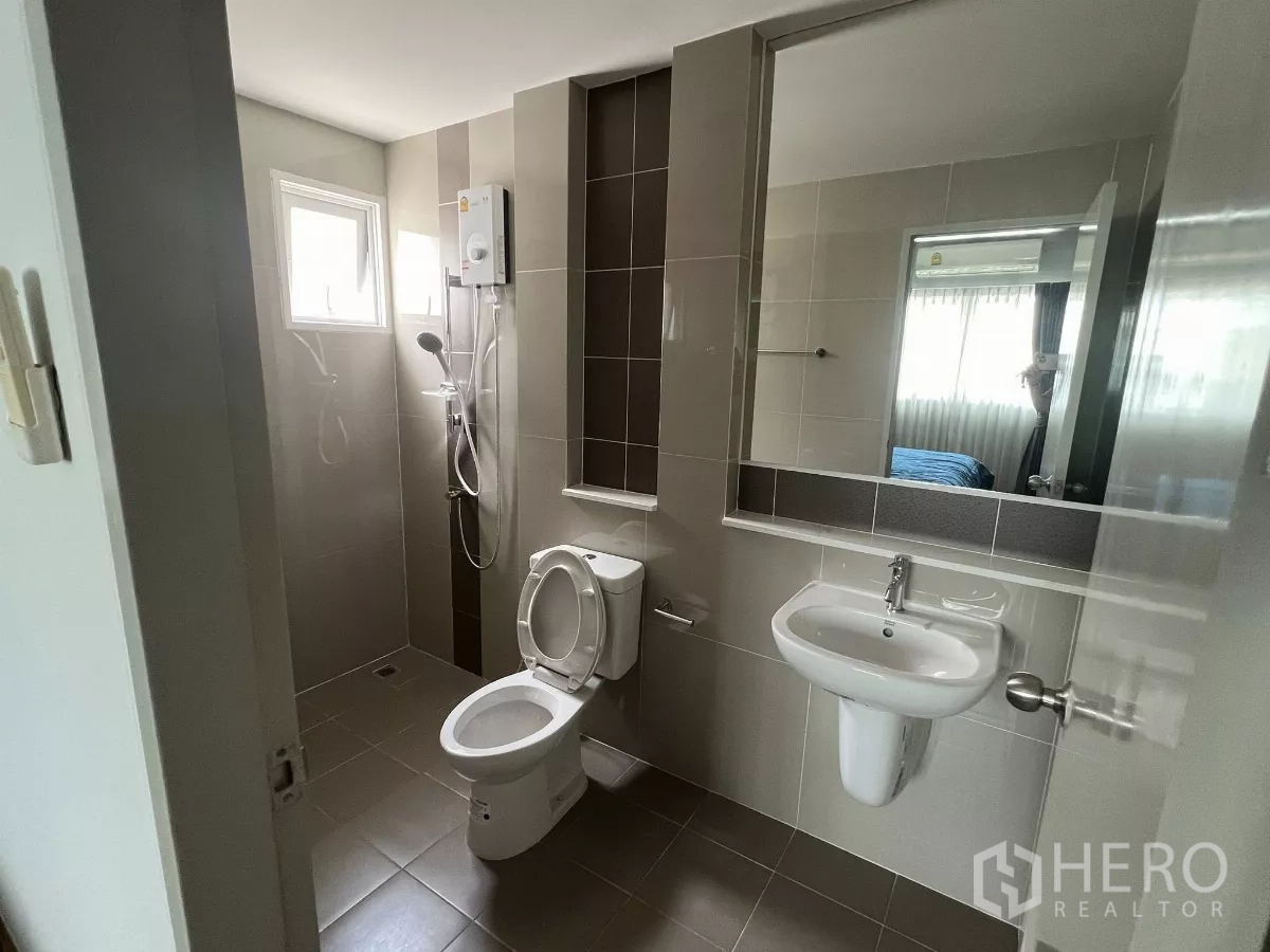 Detached House for rent or sale in Don Mueang, Bangkok - Tiled bathroom with walk‑in shower, water heater, toilet, wall mirror and small window.