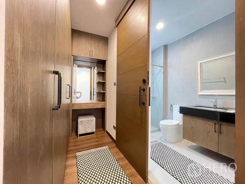 Townhouse for rent - Walk-in closet corridor with vanity leading to a bright bathroom with glass shower.