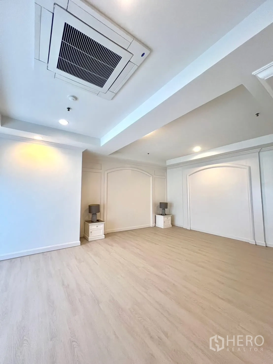 Condominium for rent in Khlong Toei, Bangkok - Spacious room with light wood flooring, cassette air-conditioning and two nightstands.