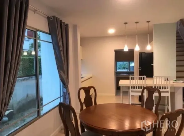 Detached House for rent in Prawet, Bangkok - Open-plan dining and kitchen view with staircase and hanging lights.