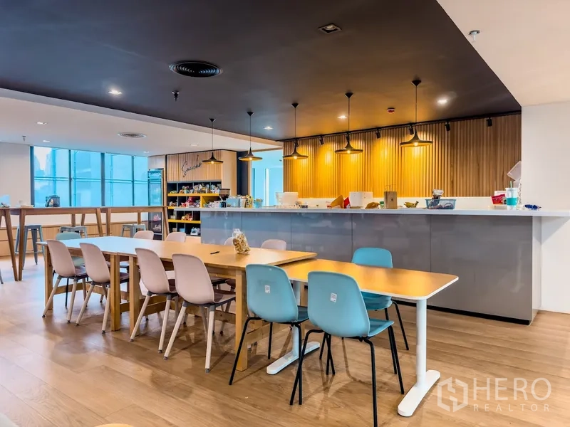 办公室 for rent in Bang Rak, Bangkok - 明亮的咖啡式茶水间，吊灯与就餐桌椅及服务台。