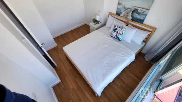 公寓 出售在Yan Nawa, Bangkok - 明亮卧室，木地板、白色床品、床头柜与通向阳台的窗。