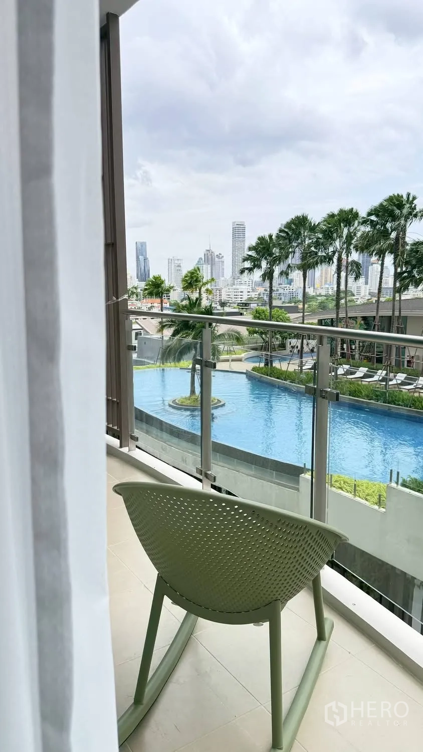 Condominium for rent in Watthana, Bangkok - Balcony overlooking a lagoon-style swimming pool and city skyline.