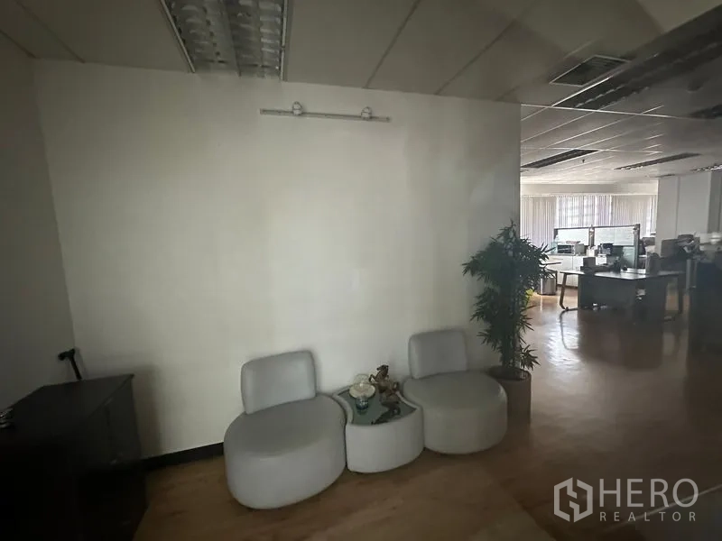 办公空间 出租在Bang Rak, Bangkok - 隔断旁的座位区，连通明亮的开放式办公室，木质地板与多张办公桌。