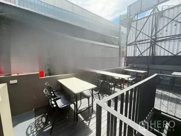 零售空间 出租在Watthana, Bangkok - 阳光充足的屋顶用餐区，数张桌子与黑色椅子靠近护栏