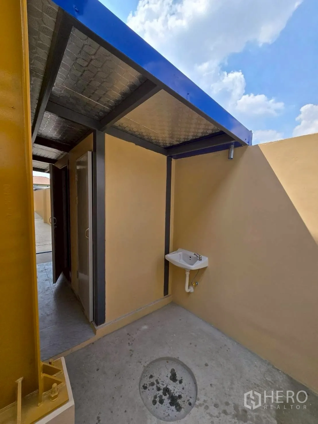 货栈 for rent in Khlong Sam Wa, Bangkok - 仓库内的半室外功能区，金属顶棚、卫生间门与墙挂式洗手盆，地面为混凝土。