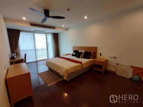 公寓 出租在Khlong Toei, Bangkok - 宽敞次卧，设大窗与书桌，木地板与柔和灯光。