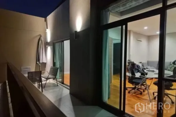 独立式住宅 出租 - 夜景阳台，壁灯、户外椅与伞，推拉玻璃门连接室内空间.